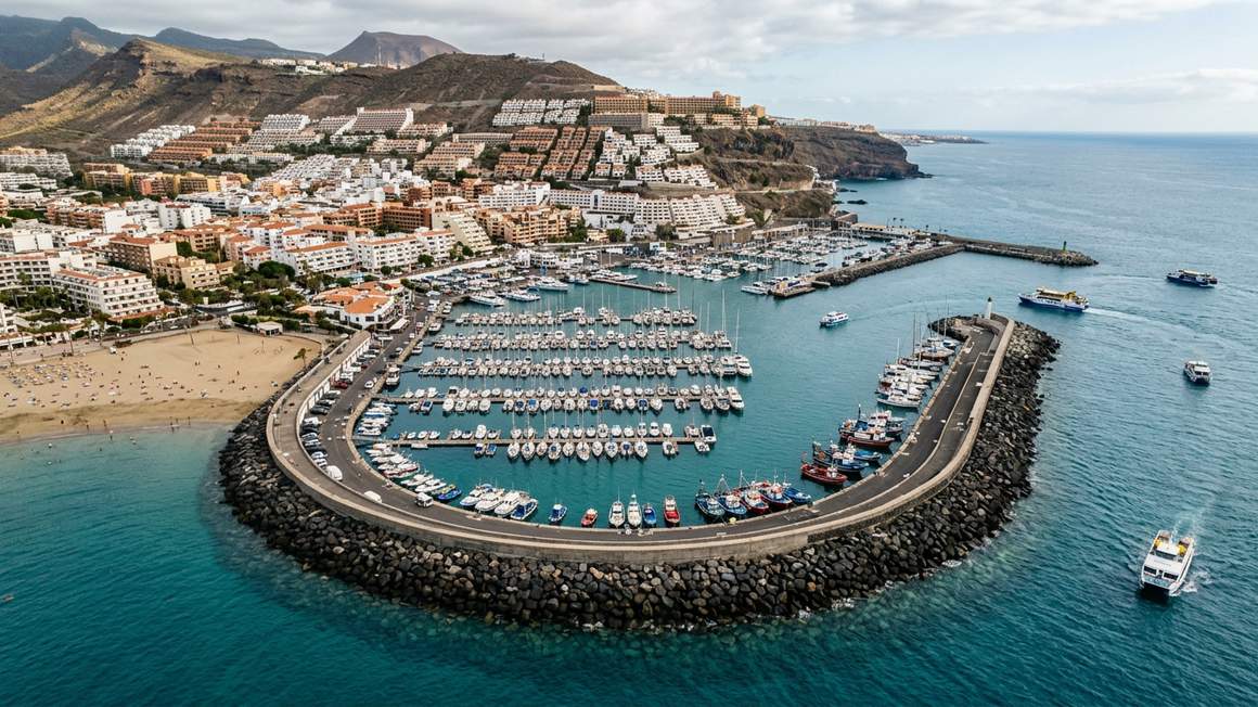 Aerial view Los Cristianos harbour showing breakwater beach and hillside town