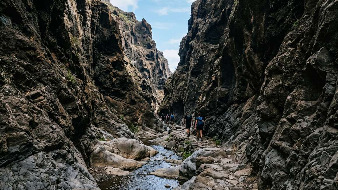 Narrow Masca gorge entrance with steep rocky walls and stream